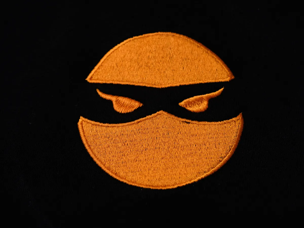 Close-up of an embroidered logo on black fabric
